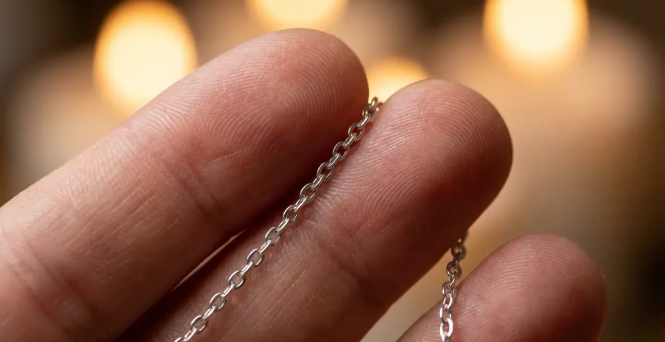 Macro shot of fingers holding a pendulum chain showing the subtle muscle movements involved in dowsing.
